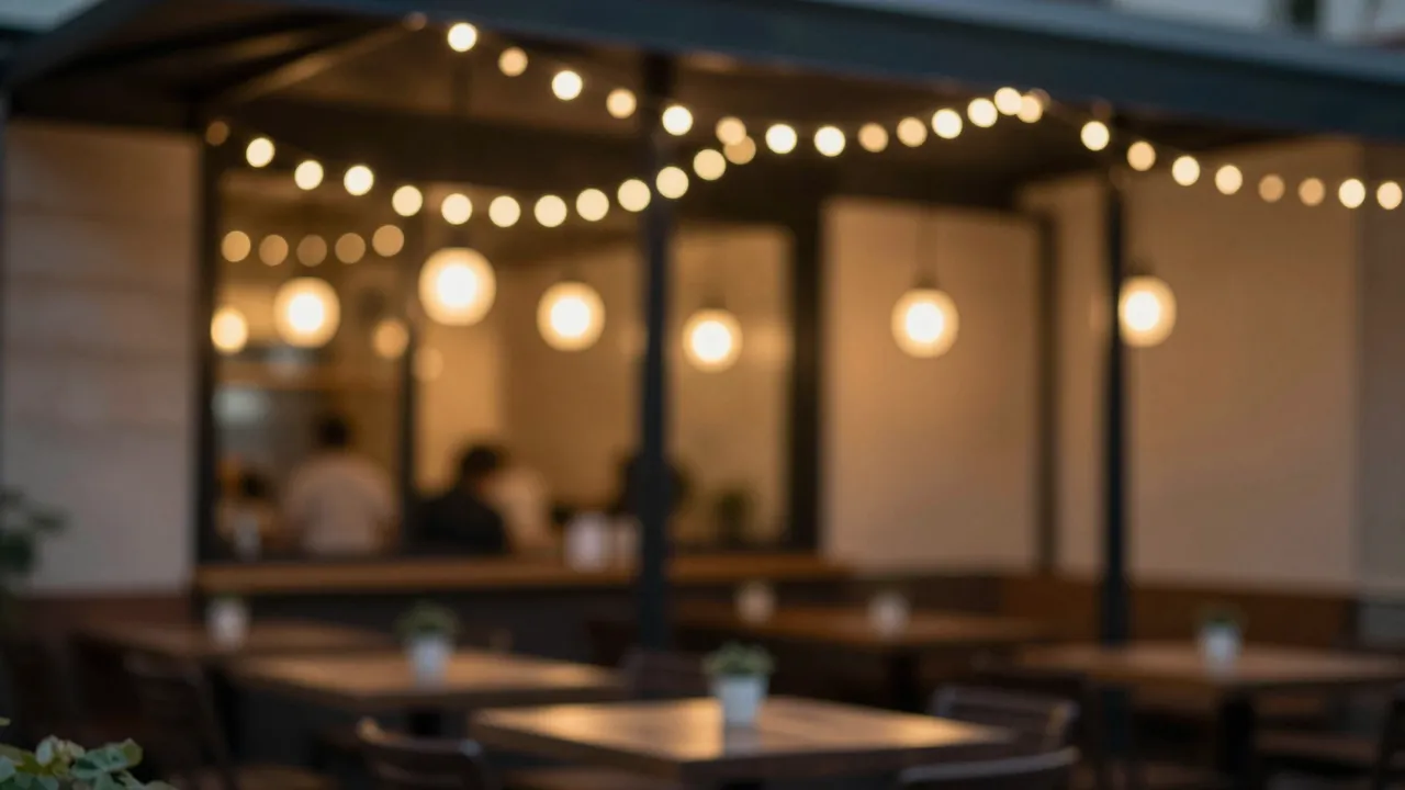 Blurred outdoor cafe patio glowing with warm string and pendant lights at night