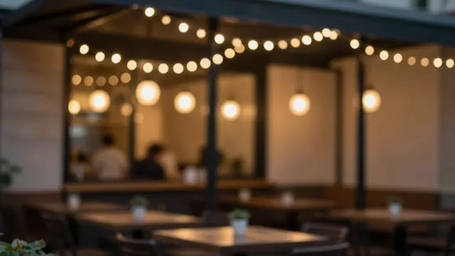 Blurred outdoor cafe patio glowing with warm string and pendant lights at night