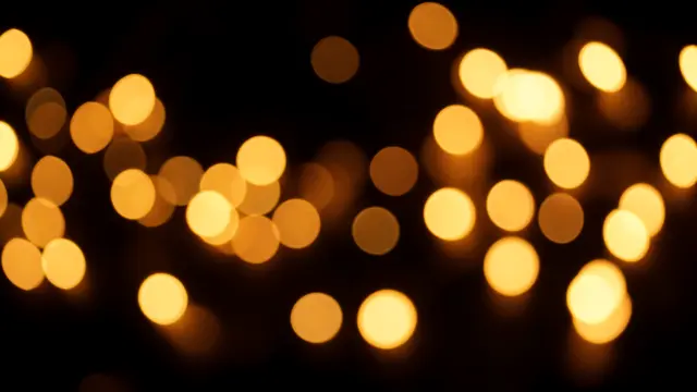 Soft out-of-focus golden and amber circular bokeh lights scattered across a solid black background