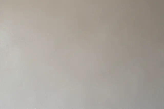Full frame close-up of a smooth warm greige microcement wall surface with subtle texture