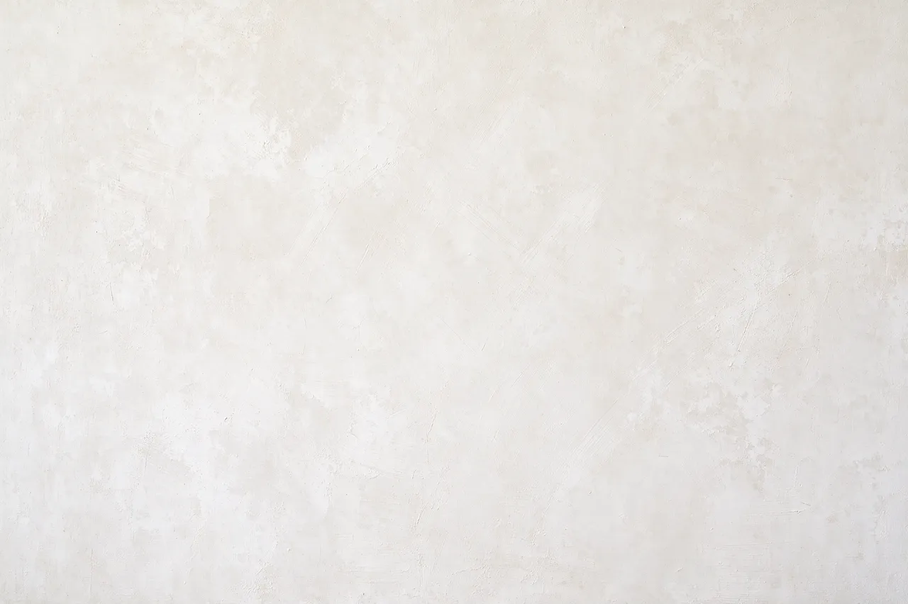 Full frame close-up of a matte warm white limewash wall with soft cloudy brush strokes