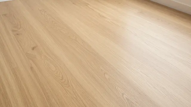 Top-down view of smooth wide light oak floorboards lit with soft warm indoor light