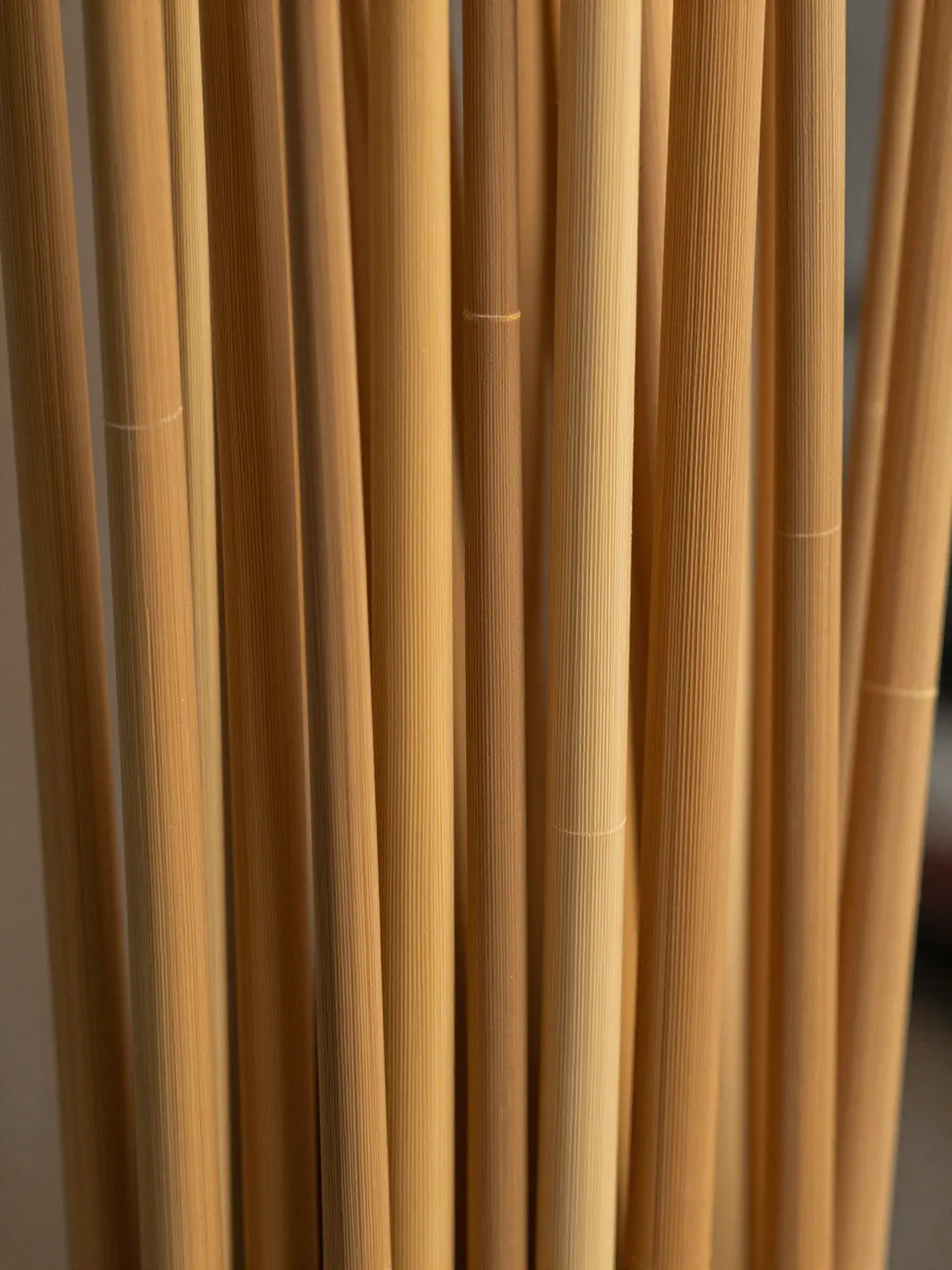 Full frame close-up of reeded glass refracting soft warm amber light into vertical upright bands