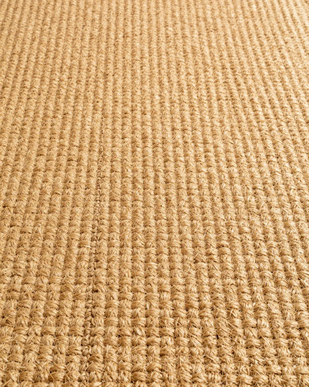 Full frame top view of coarse ribbed woven warm golden tan sisal carpet
