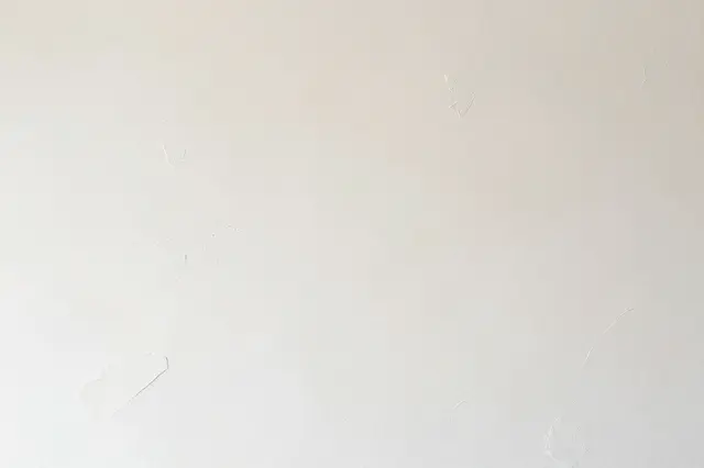 Full frame view of a warm white skip-trowel plaster wall with subtle irregular raised texture patches
