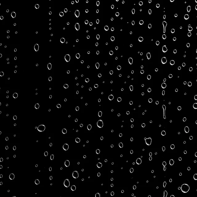 Clear water droplets of varying sizes rest against a solid pure black backdrop
