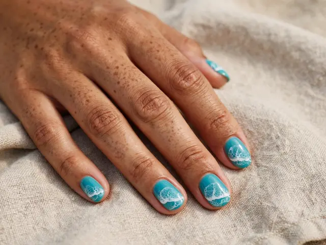 A freckled mixed-race hand with turquoise wave nail art rests on beige linen fabric.