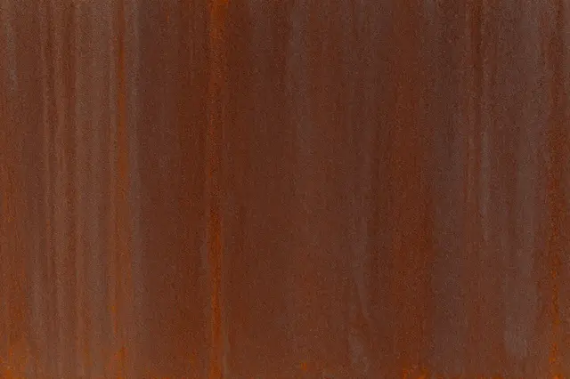 Full frame close-up of a deep rust brown weathered corten steel surface with subtle vertical streaks