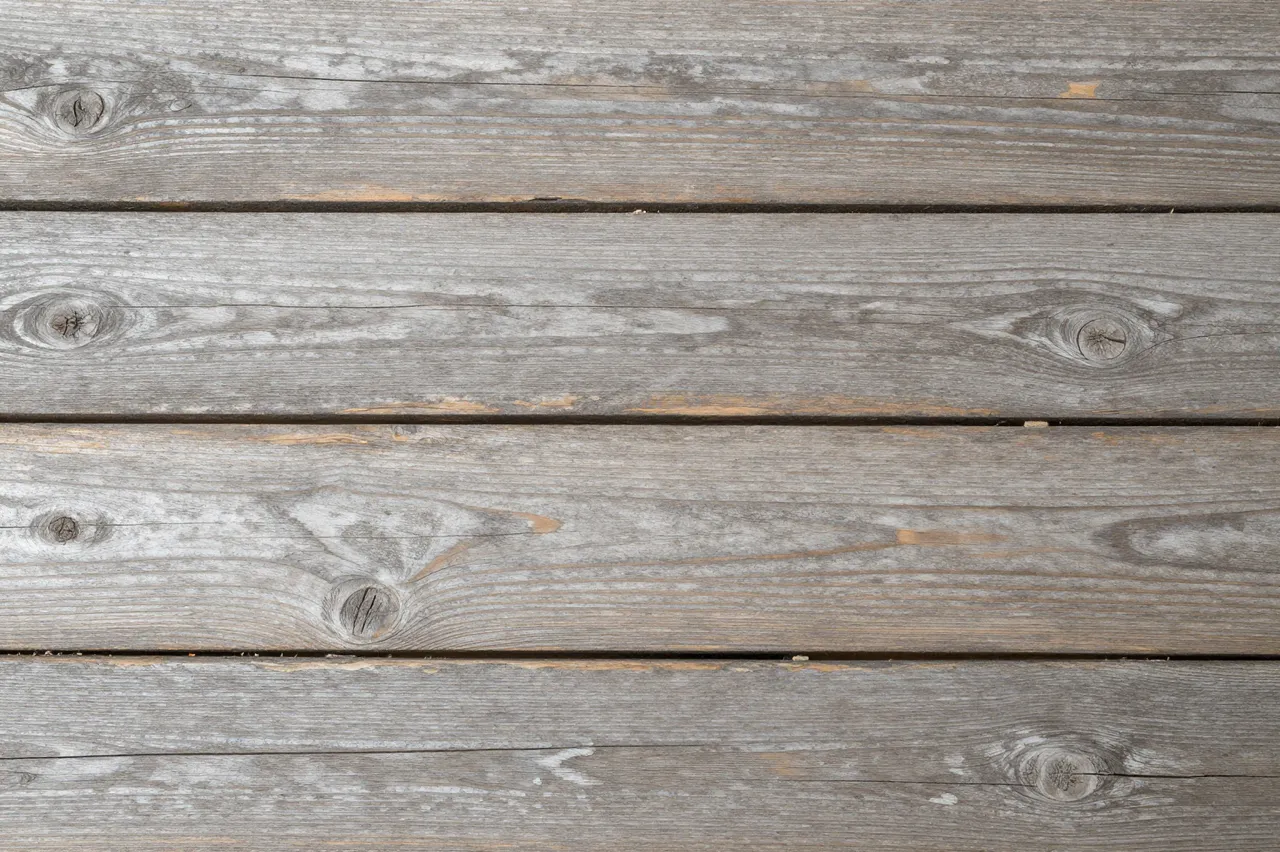 Top view of parallel weathered gray wooden planks with natural grain and knots