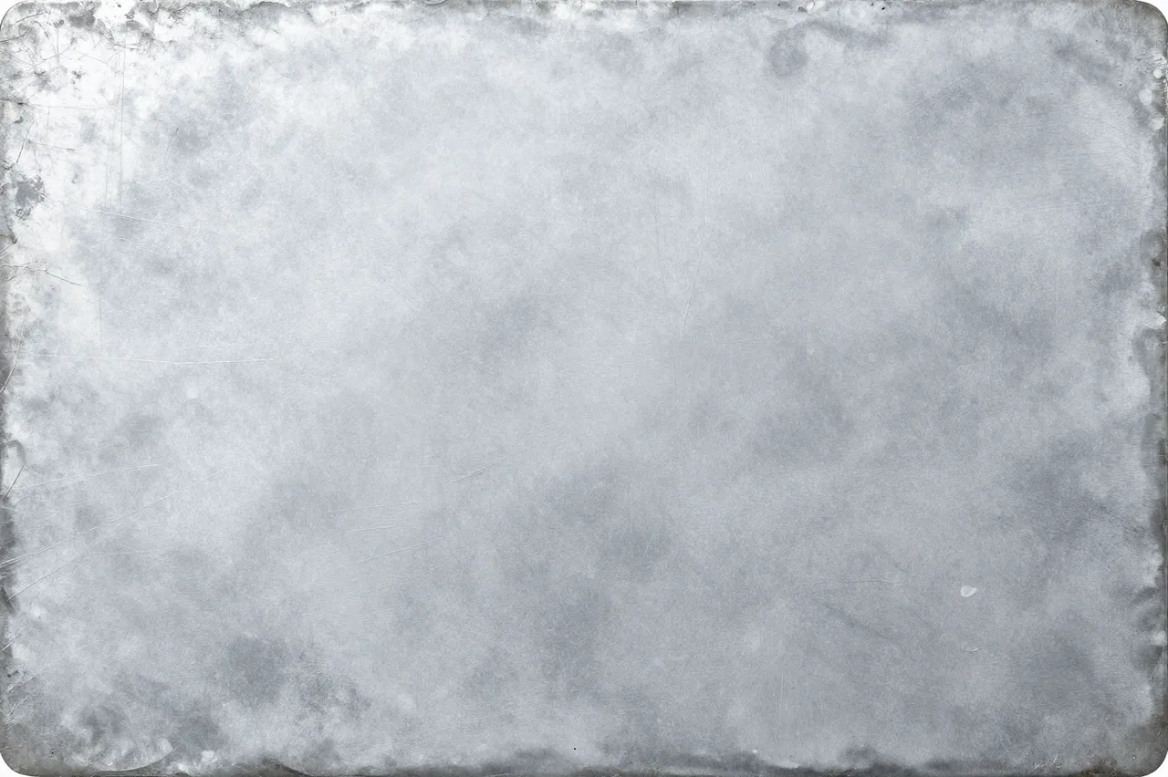 Full frame close-up of a zinc sheet with white oxidation bloom and soft gray mottling under flat even light