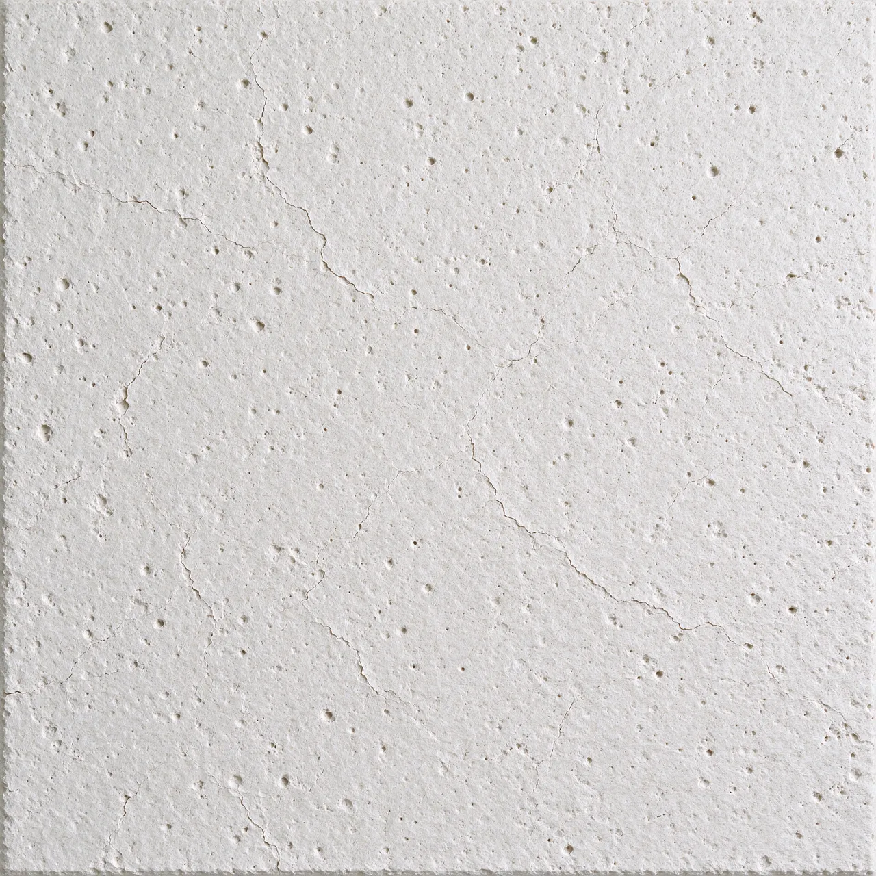 Full frame close-up of a white mineral fiber acoustic panel with fine fissures and small pinholes under even lighting