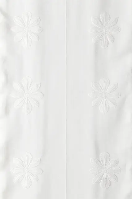 Full frame close up of tone-on-tone white floral embroidery stitched onto textured white linen fabric