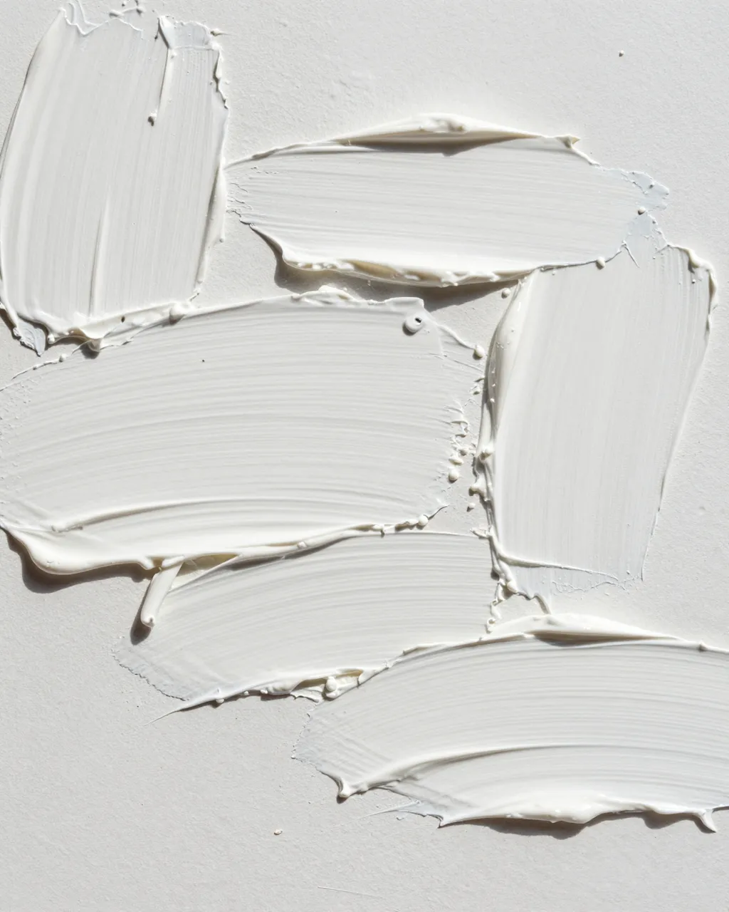 Full frame close-up of thick white impasto paint strokes lit by raking light, showing distinct palette knife texture ridges.