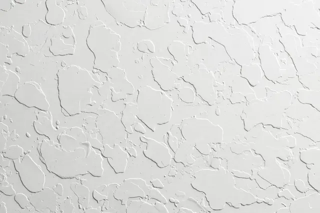 Full frame close-up of white knockdown plaster drywall texture with raised splatter blobs and smooth gaps