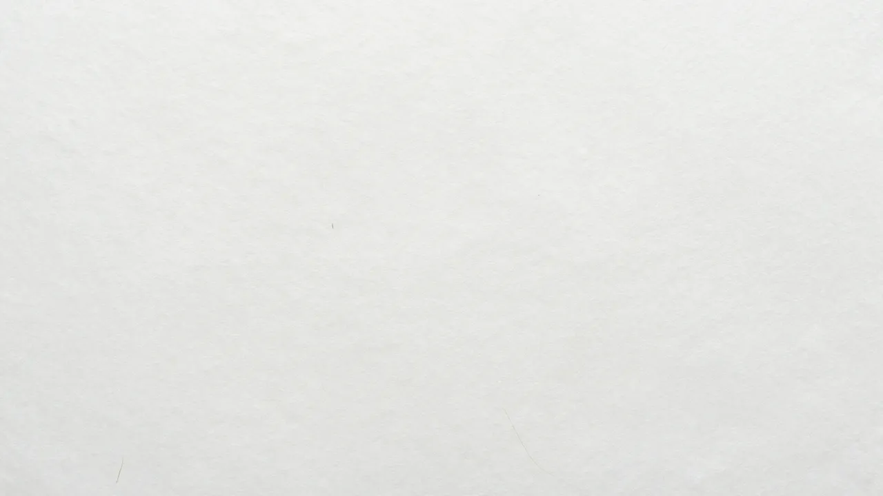 Full frame close-up of matte white kraft paper with faint natural tan fiber details