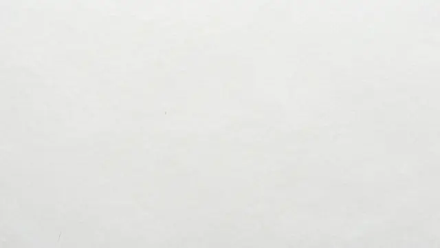 Full frame close-up of matte white kraft paper with faint natural tan fiber details