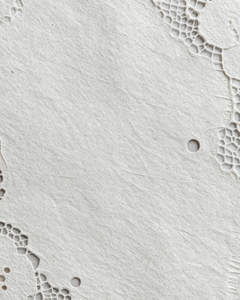 Close-up full frame of textured white lace paper with delicate holes and wispy natural fibers