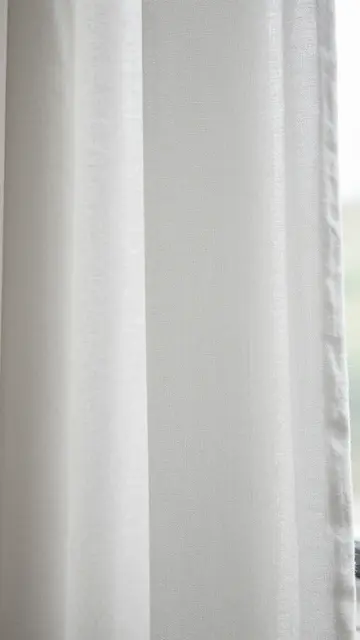Close-up of textured white linen sheer fabric lit by soft natural window light