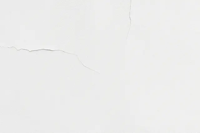 Smooth white plaster wall with subtle, thin natural cracks across its surface