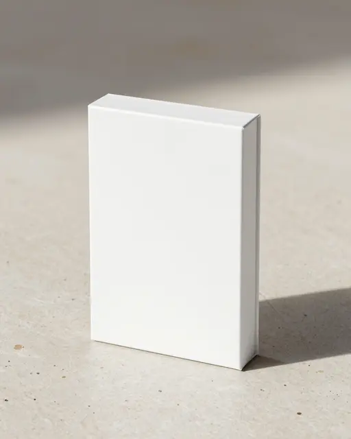 A blank upright white rectangular box rests on a light beige stone surface with a soft cast shadow