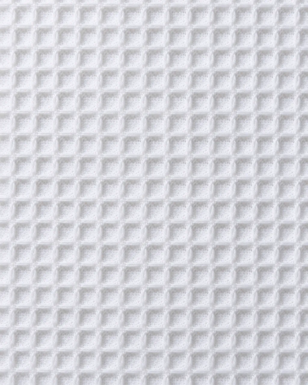 Full frame close-up of uniform white waffle weave cotton fabric with raised square ridges