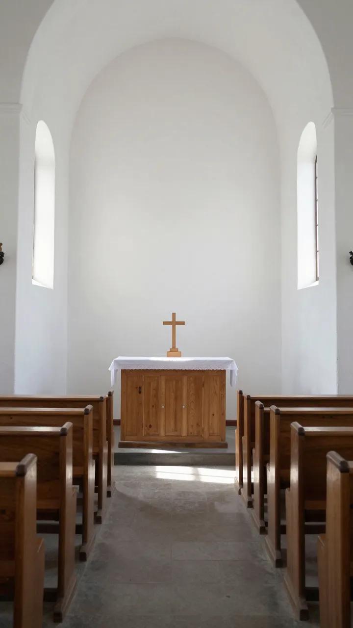 Sunlit aisle between wooden pews leads to a simple altar in a small white chapel