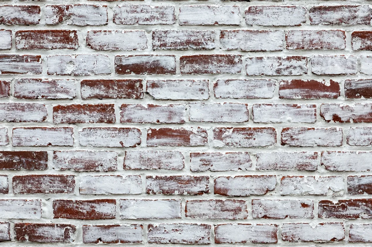 Full frame close up of an old brick wall with thin chalky white wash over exposed red bricks