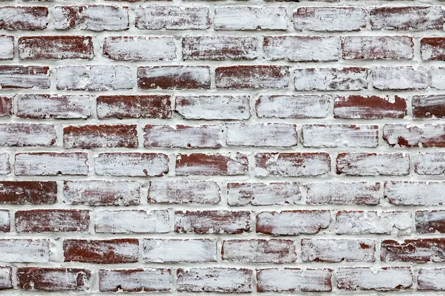 Full frame close up of an old brick wall with thin chalky white wash over exposed red bricks