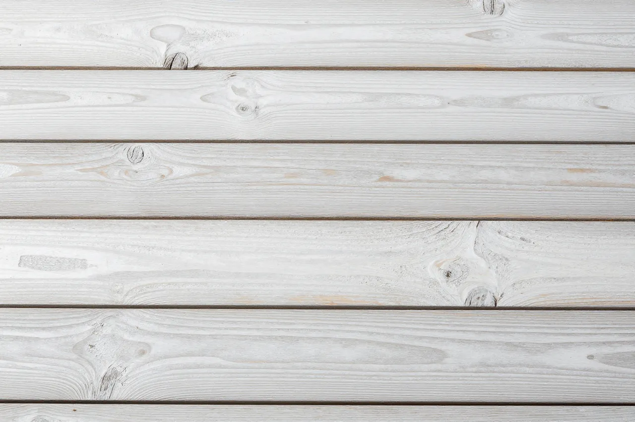 Top view of parallel horizontal whitewashed wooden planks with visible natural wood grain and knots
