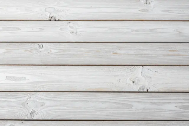 Top view of parallel horizontal whitewashed wooden planks with visible natural wood grain and knots