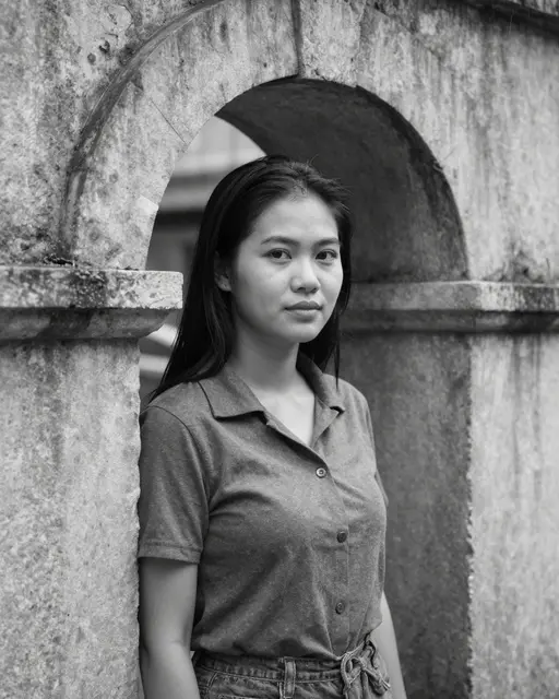 Black and white portrait of a Southeast Asian woman standing under a weathered stone archway