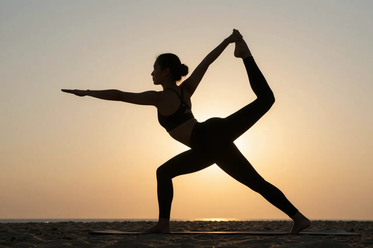 Silhouette of a woman holding a yoga pose on a sandy beach at golden sunset