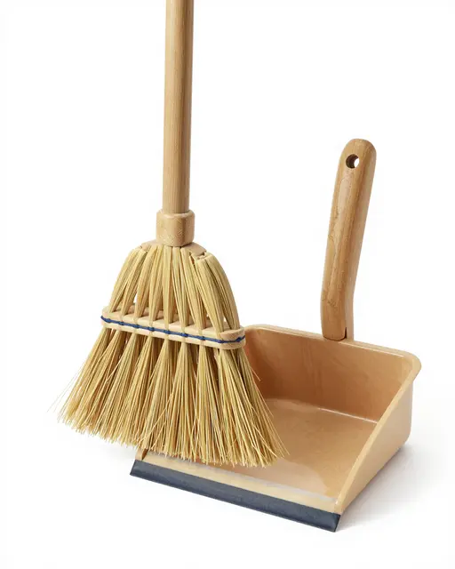 Wooden broom with natural bristles sits next to a matching wood dustpan on a pure white studio background