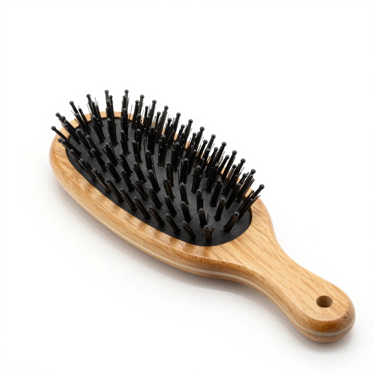 An oval wooden hairbrush with black bristles rests on a plain white background.
