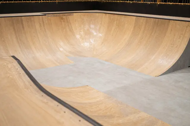 Empty wooden skate bowl ramp with string lights lining the upper edge after dark