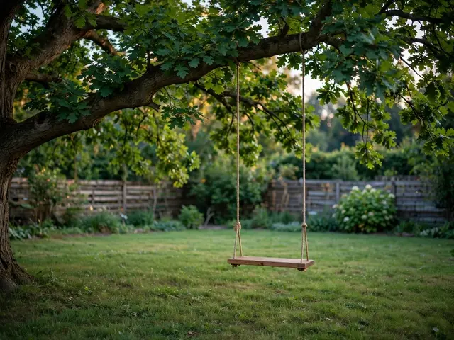 A plain wooden swing hangs from a large oak tree over a grassy backyard at summer sunset