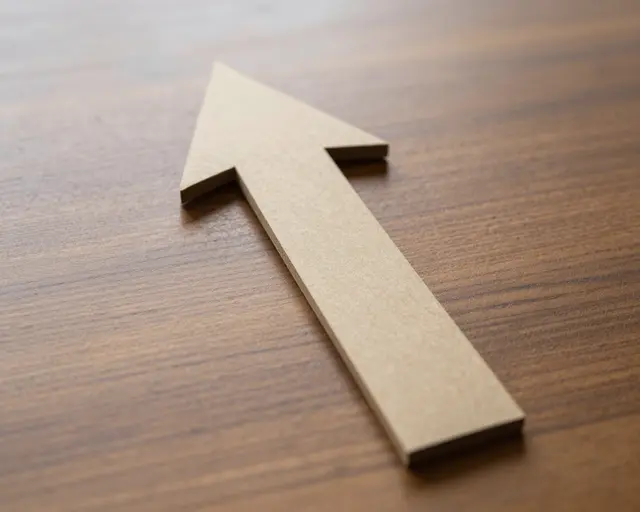 A plain light wood upward-pointing arrow rests diagonally on a dark grained wooden table