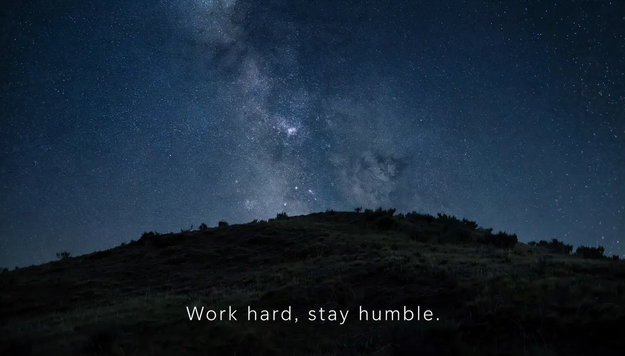 Wide desktop wallpaper of a starry night sky over a dark hill with the text "Work hard, stay humble."