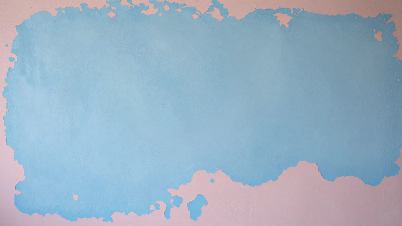 Grunge wall surface with chipped pale blue paint revealing soft pink undercoat under flat even lighting