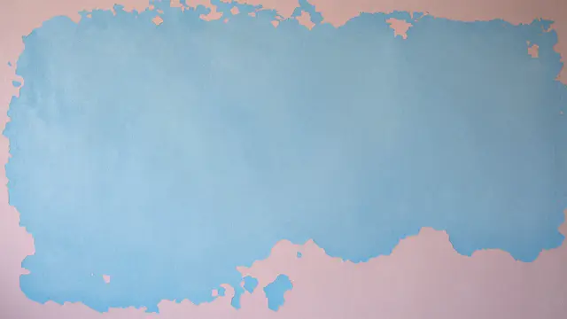 Grunge wall surface with chipped pale blue paint revealing soft pink undercoat under flat even lighting