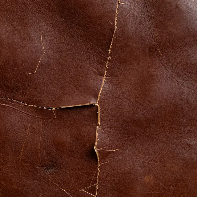 Macro close-up of deep brown old leather with cracks, scratches and aged patina