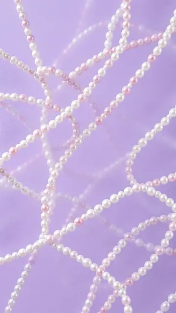 Looping pale pink and white pearl strands rest over a frosted soft lilac background