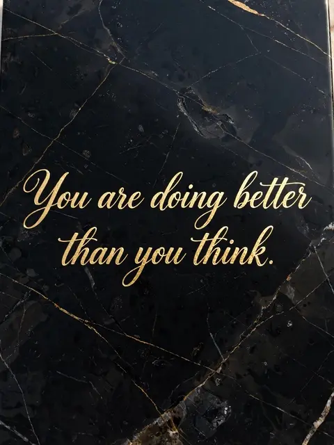 Gold foil script reading "You are doing better than you think." set against polished black veined marble