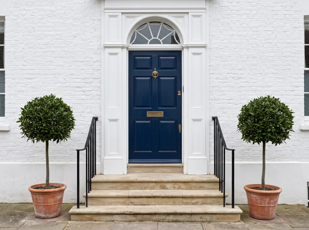 A white townhouse entrance with a navy-blue front door