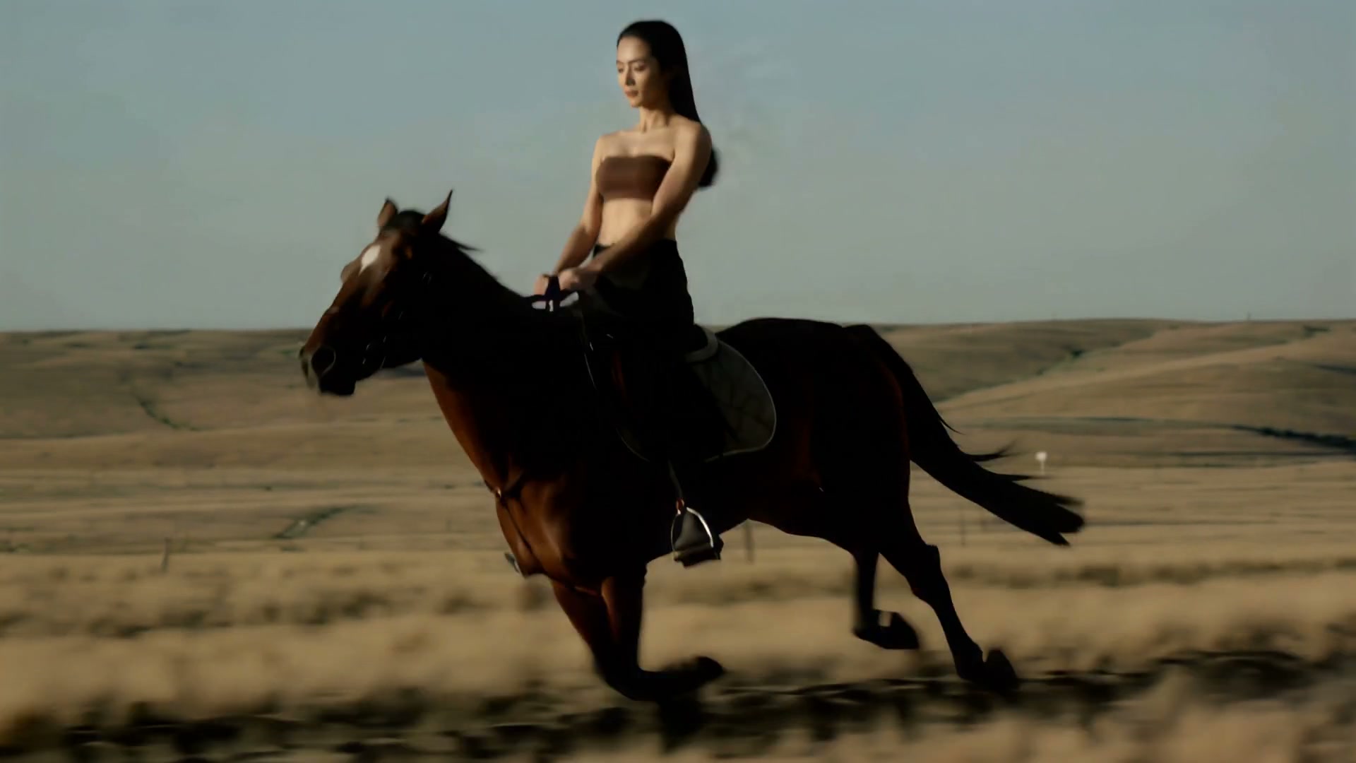 Woman riding a dark horse at full gallop across a desert plain.