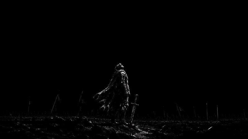 Silhouetted armored medieval knight stands on a post-battle battlefield beside his sword, looking...