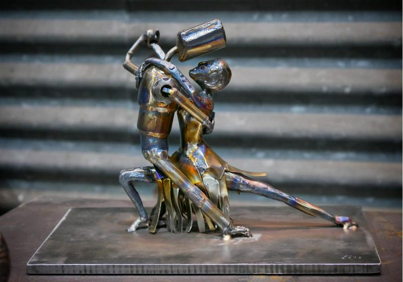 Welded heat-patinated metal sculpture of a tango dancing couple on a steel base
