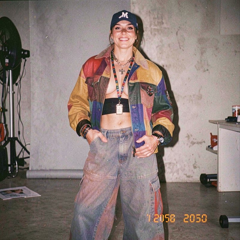 Smiling woman in retro streetwear poses for a grainy 35mm film style studio portrait