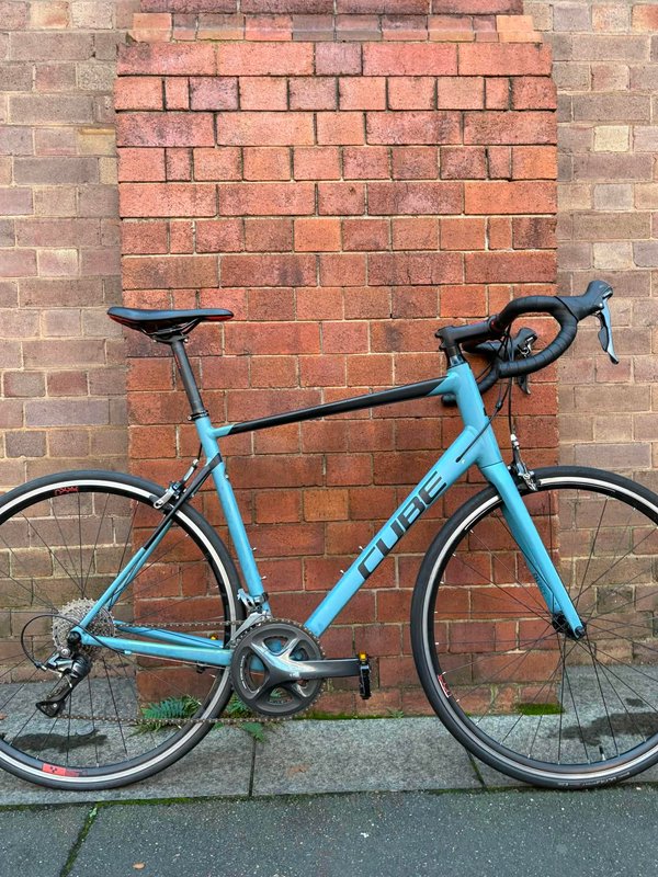 Blue Trek road bike leaning against a red brick wall.