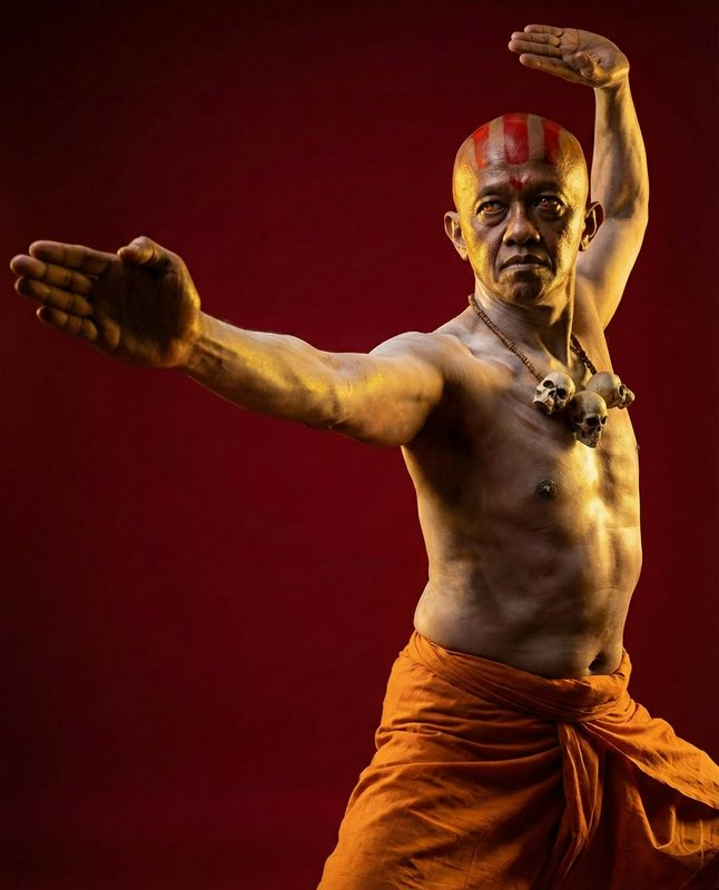 Shaolin martial artist holding a kung fu stance, with traditional sacred tilak marks and skull ne...
